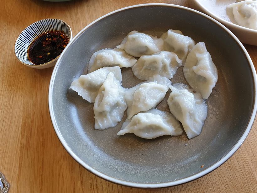 A bowl of boiled dumplings with chilli dipping sauce