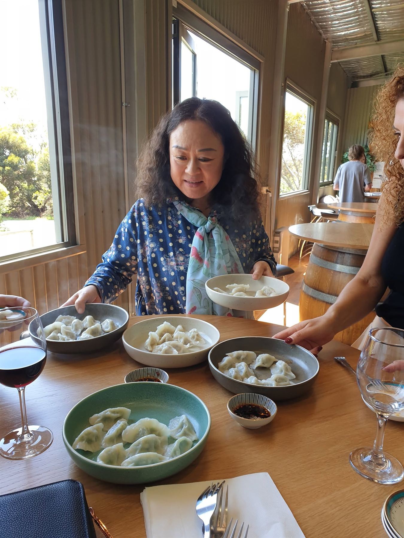 Wei serving plates of handmade dumplings at a table in the cellar door